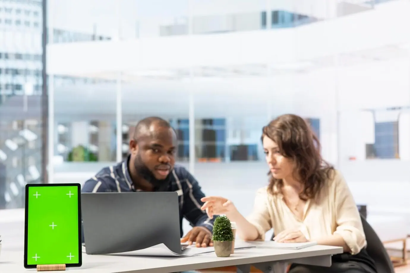 Unternehmer prüft zusammen mit einem Immobilienmakler Baupläne neben einem isolierten Display.